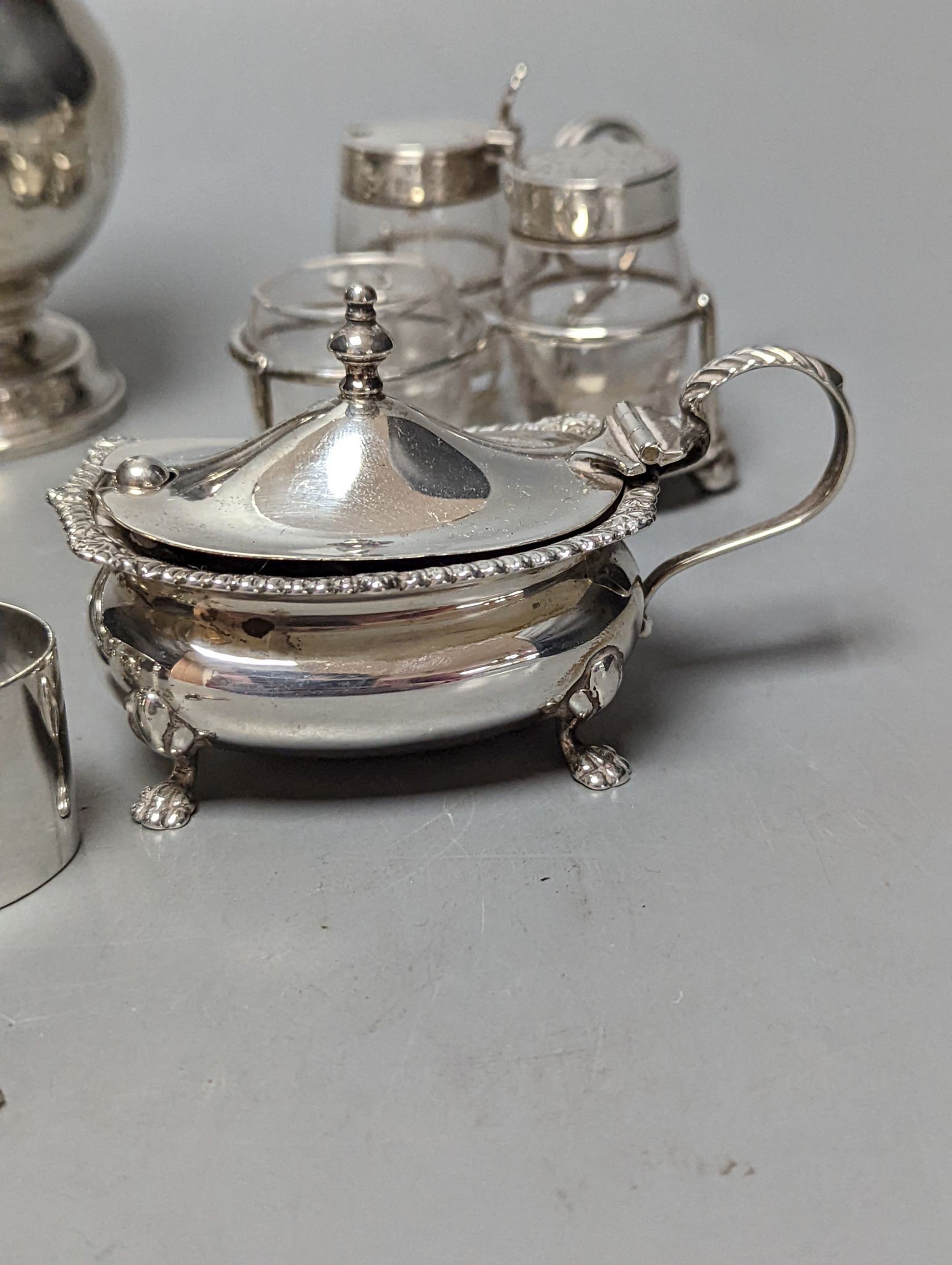 A late Victorian small silver condiment stand with three glass condiments, London, 1883, 49mm, other minor condiments and a silver sugar caster.